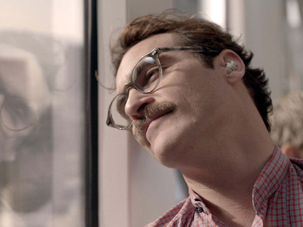 Theodore resting against a train window while listening through an earpiece